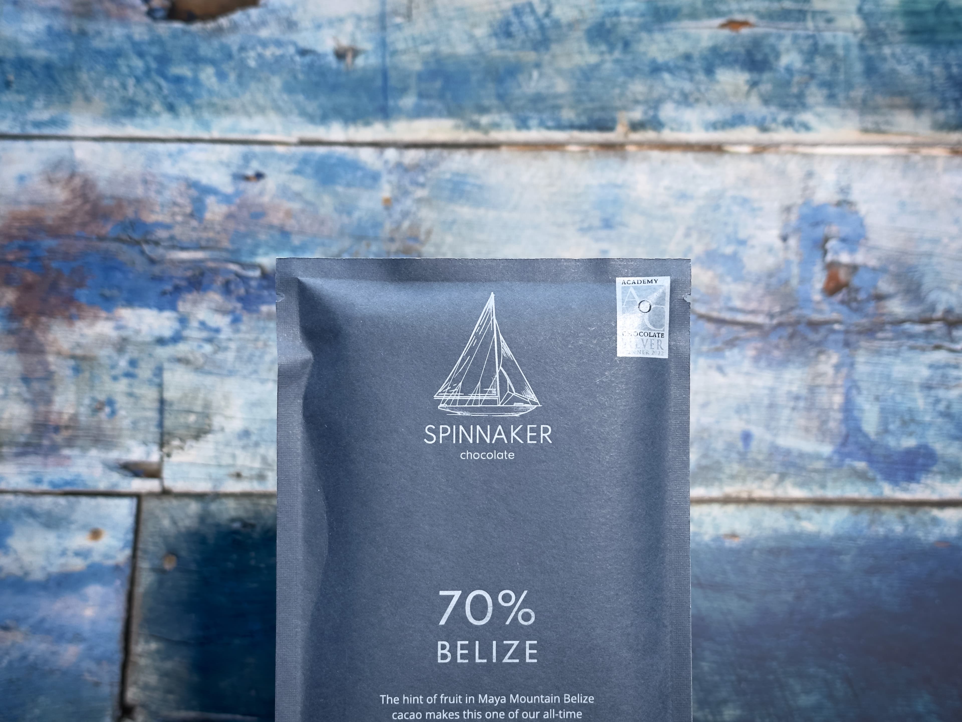 70% Belize bar made by Spinnaker Chocolate in the United States in front of warn deck boards