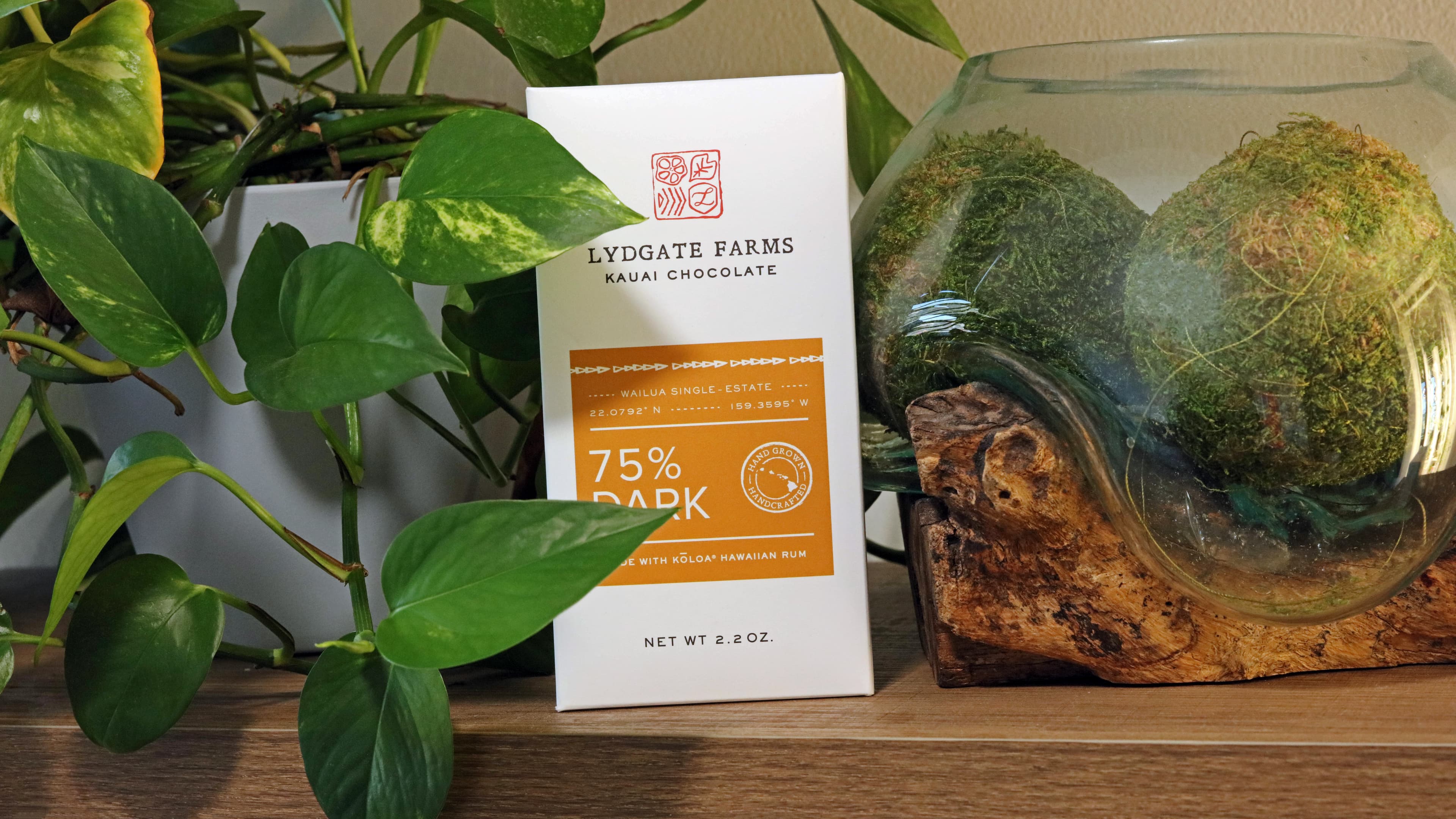 75% Dark Made with Koloa Hawaiian Rum bar made by Lydgate Farms in the United States on a shelf with drift wood and green plants