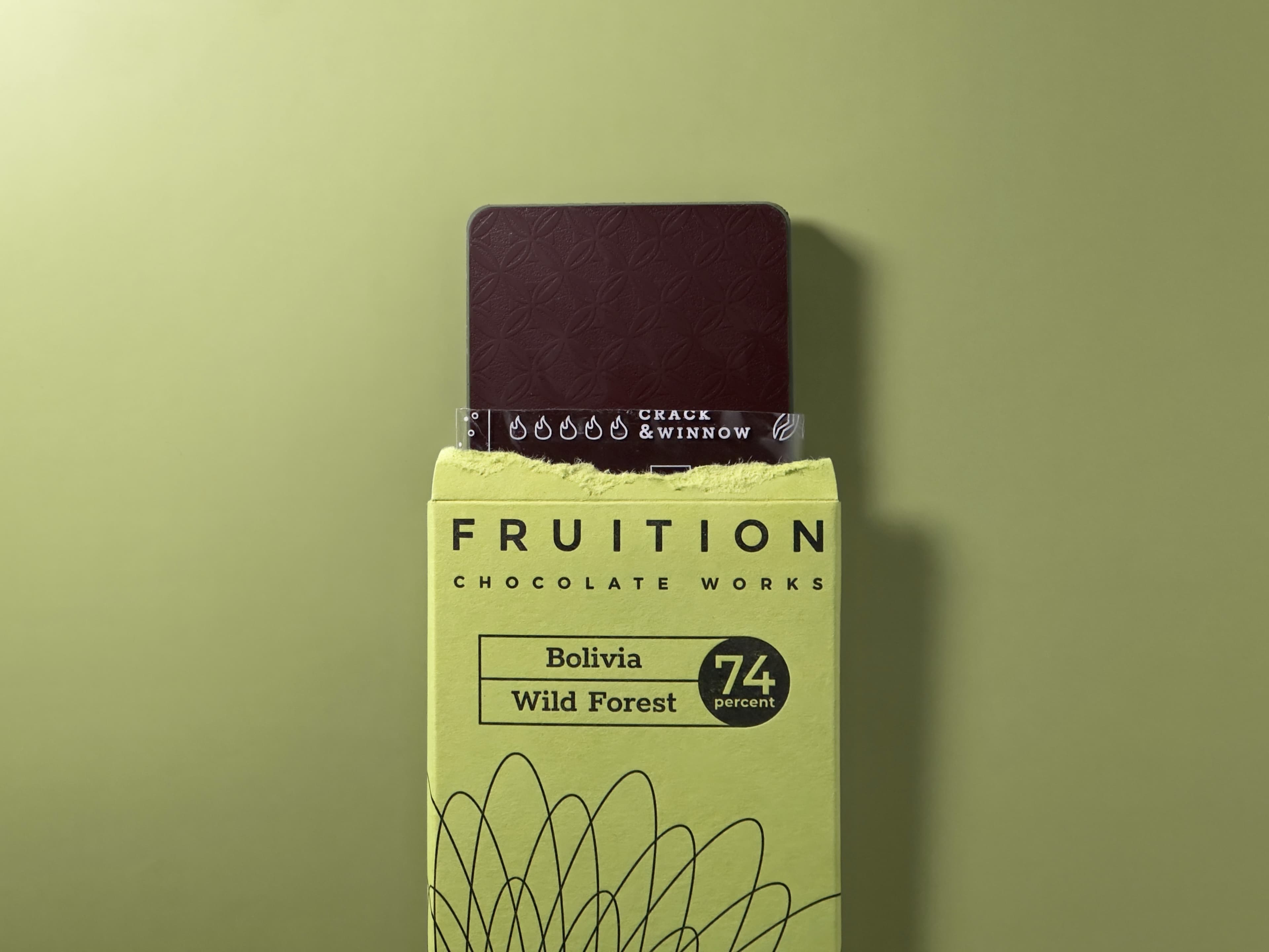 Bolivia Wild Forest Dark 74% bar made by Fruition Chocolate Works in the United States arranged torn open with the bar exposed