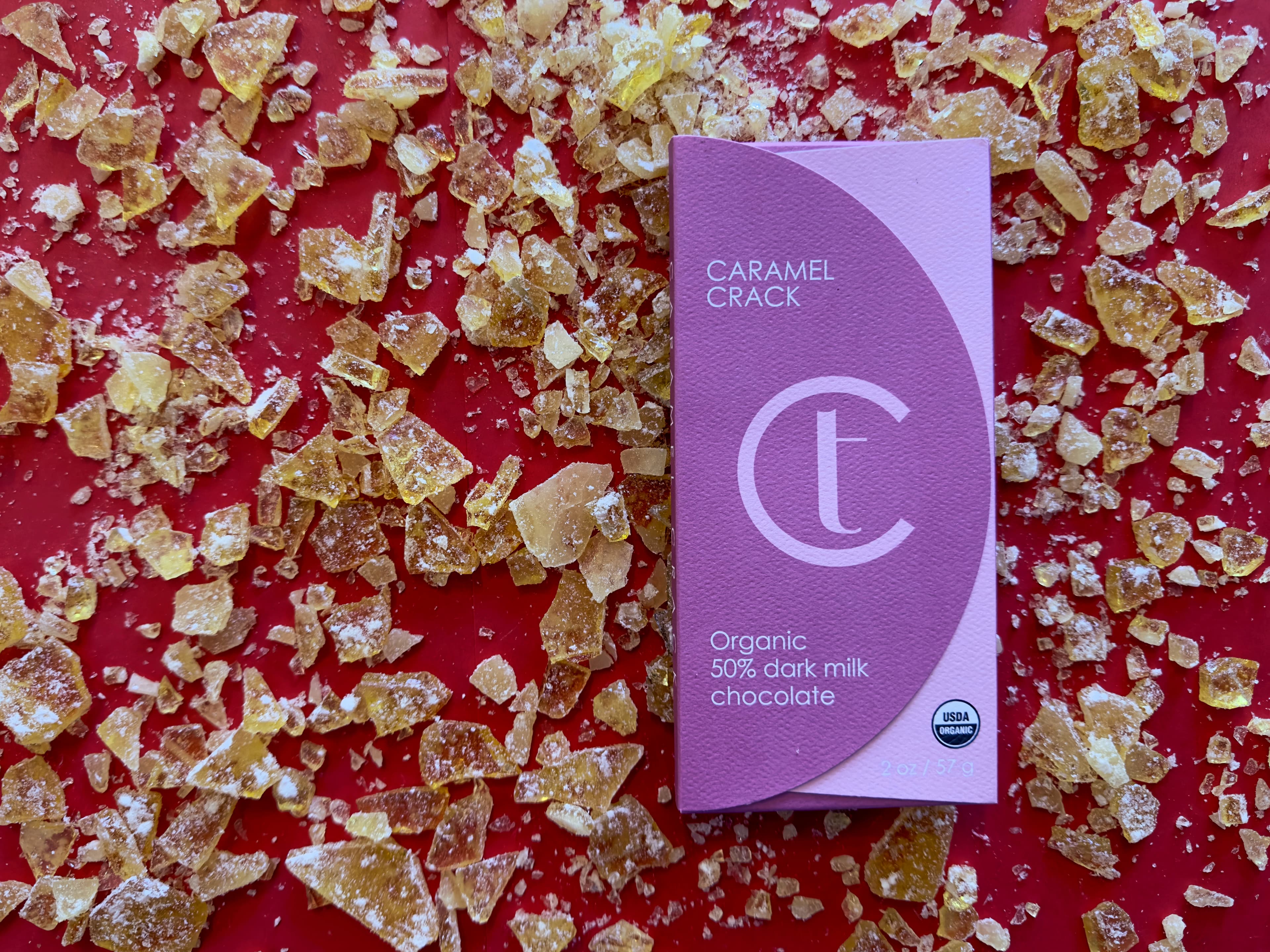 Caramel Crack Organic 50% dark milk chocolate bar from Terroir Chocolate on shattered sugar glass and a red background