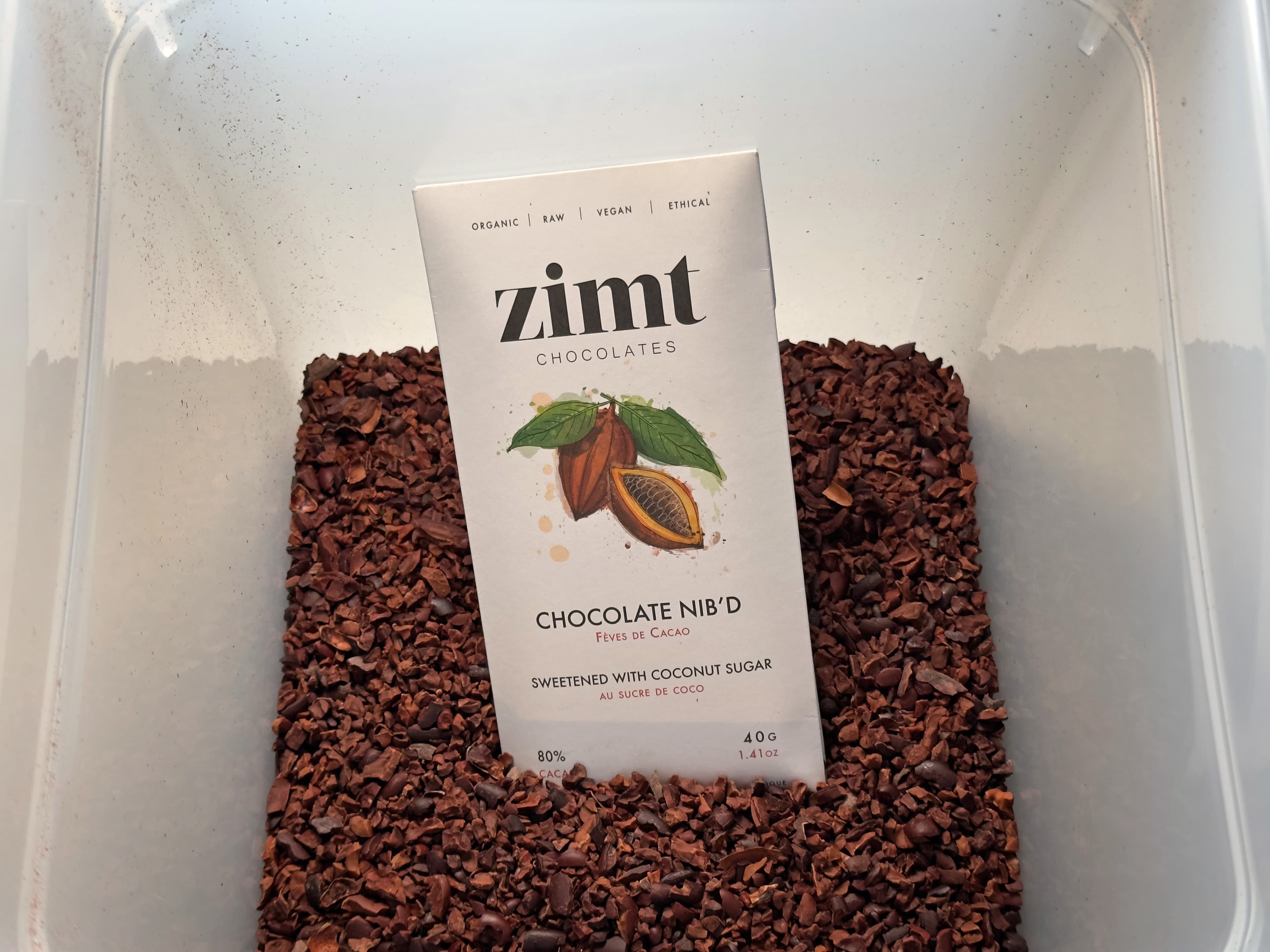 Chocolate Nib'd bar made by Zimt Chocolates in a bucket of cacao nibs