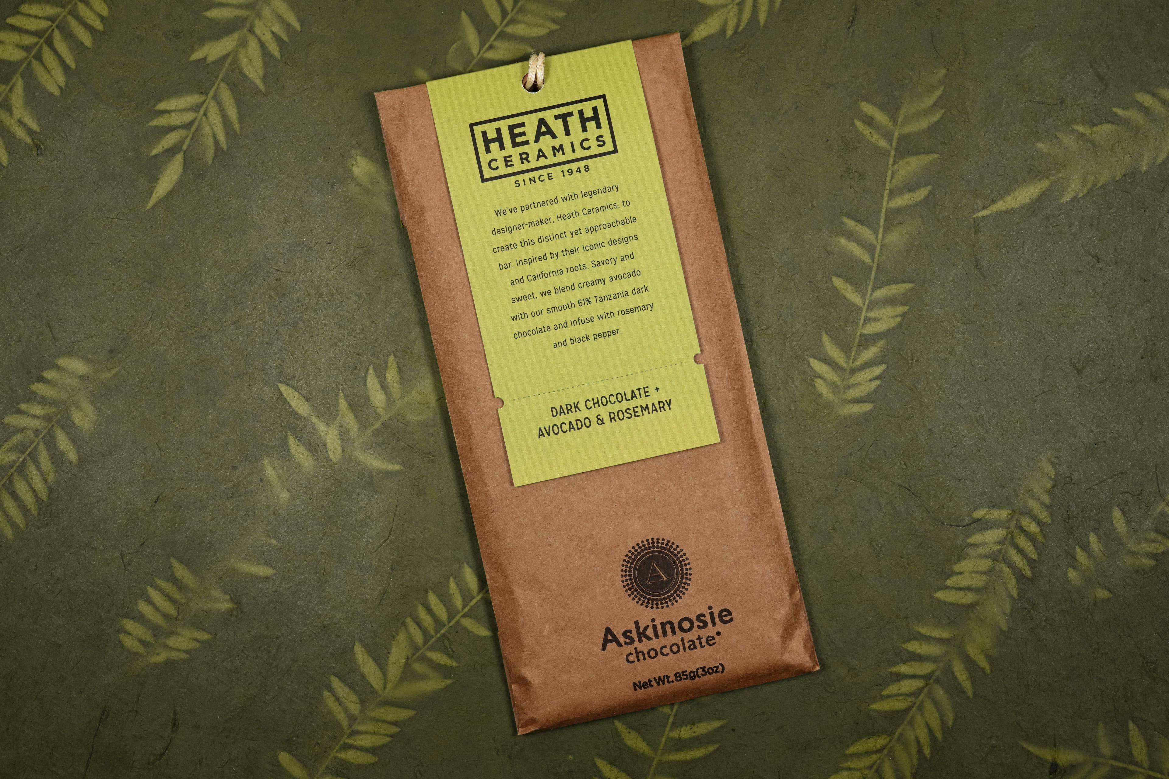 Dark Chocolate + Avocado & Rosemary Heath Ceramics Collabaration Bar bar made by Askinosie Chocolate in the United States on a green background with leaves