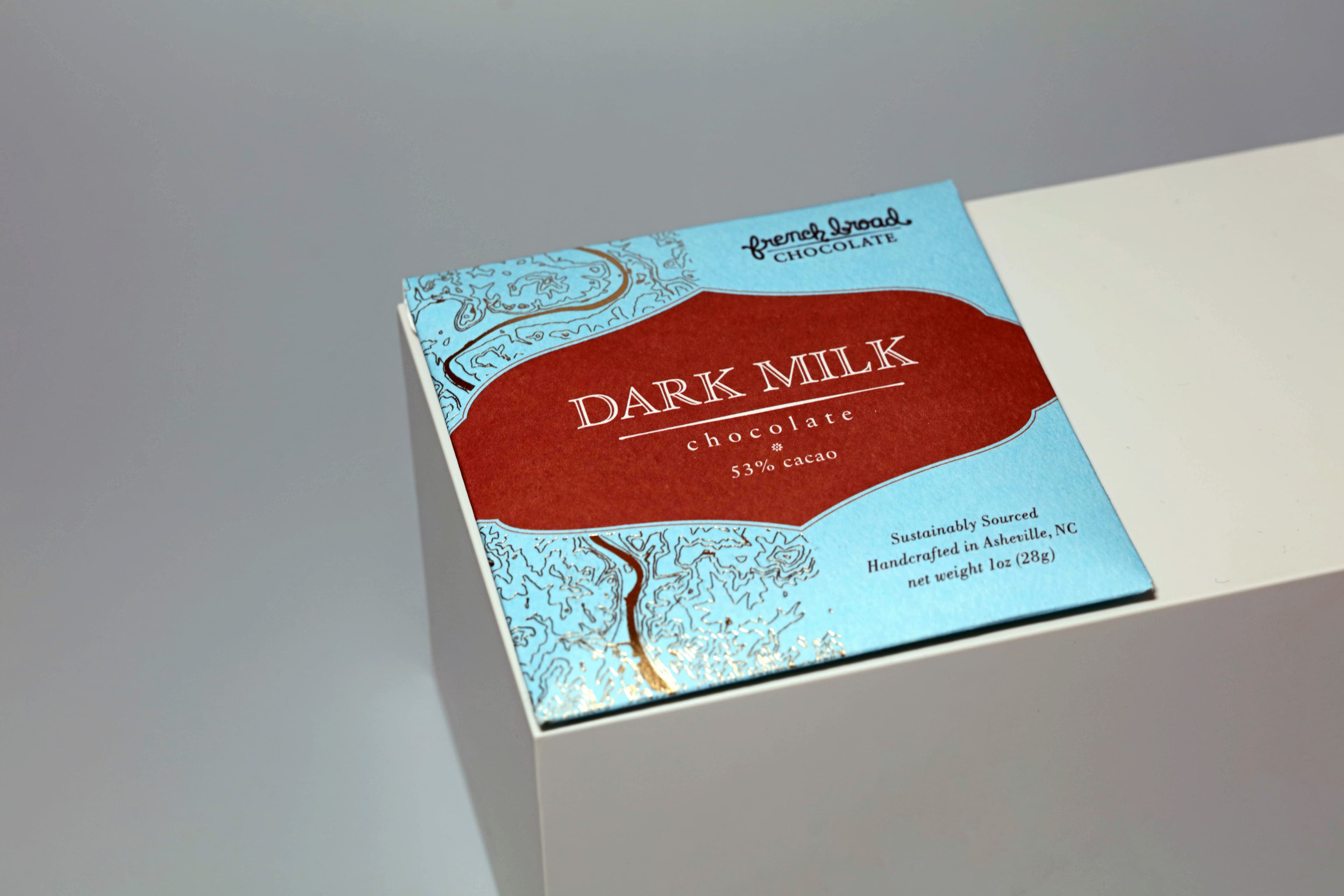 Dark Milk bar made by French Broad Chocolate in the United States with on a white volume