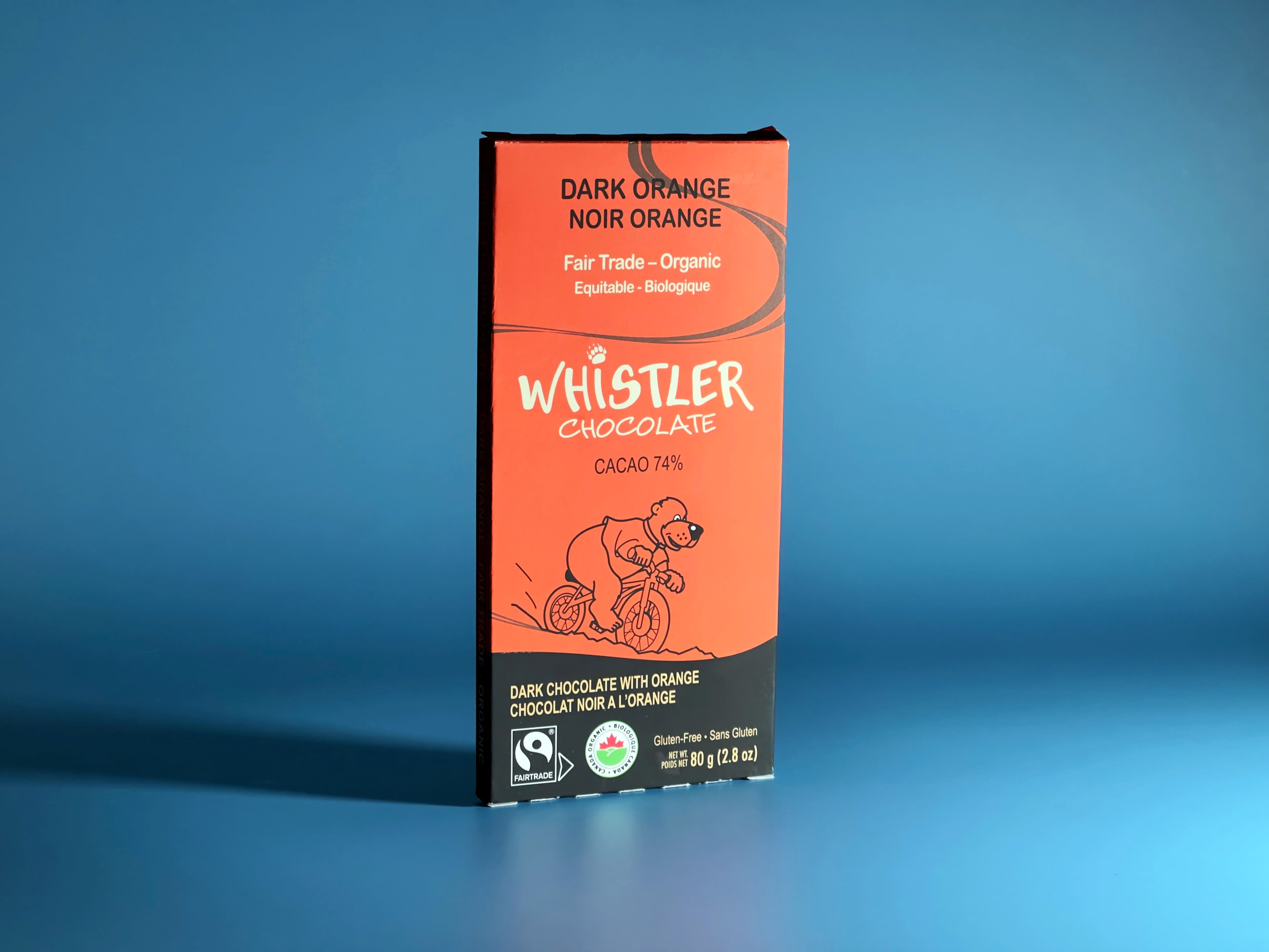 Dark Orange bar made by Whistler Chocolate in Canada standing up with a blue background