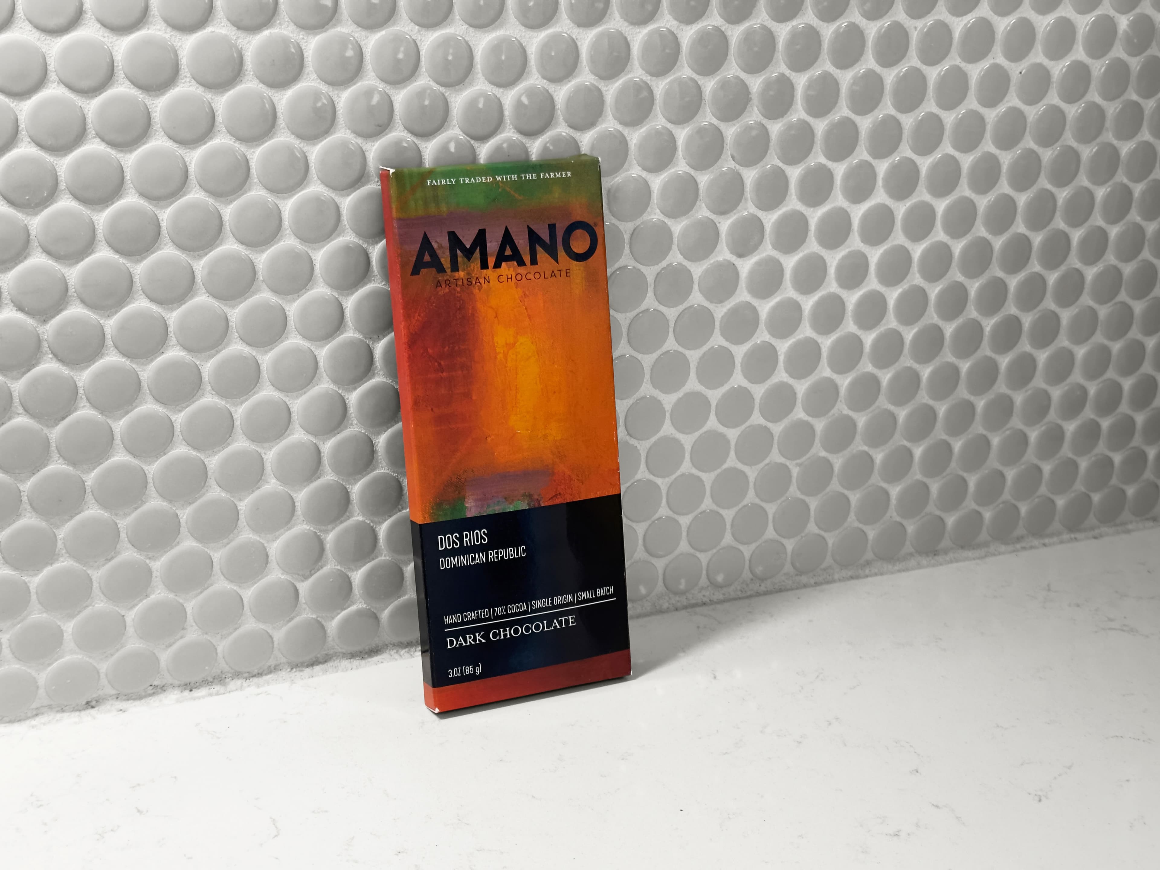 Dos Rios Dominican Republic bar made by Amano Artisan Chocolate in the United States propped up against a light gray circular tile background