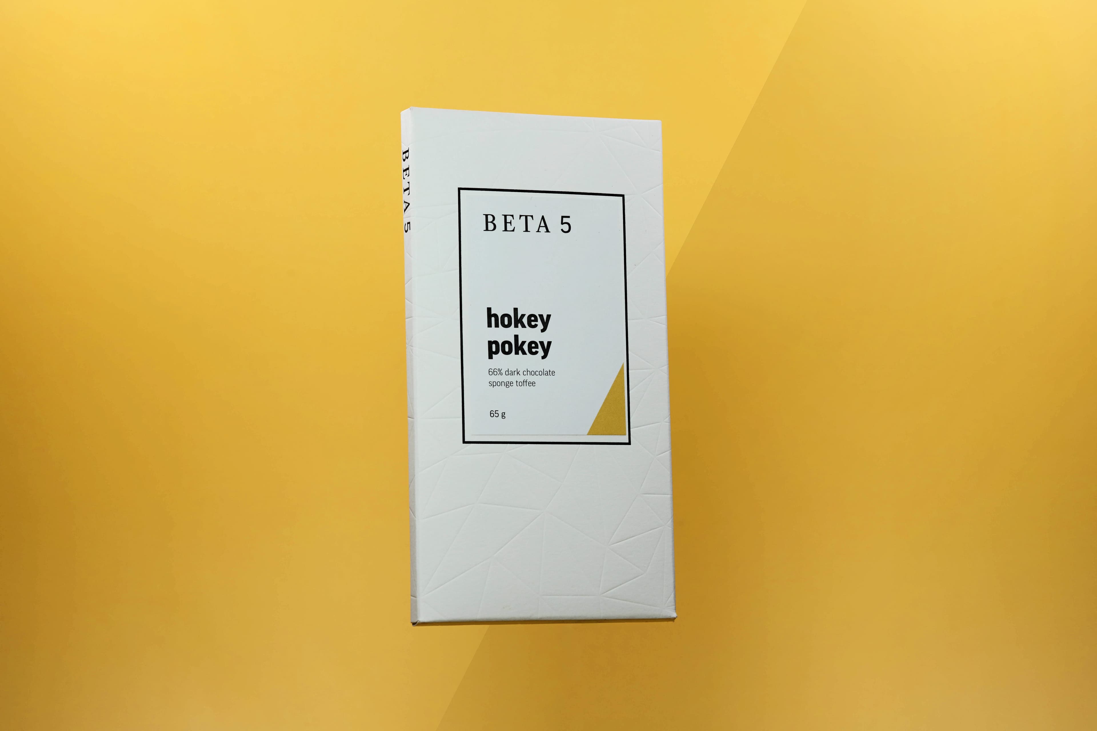 Hokey Pokey 66% Dark Chocolate Sponge Toffee bar made by BETA5 in Canada on a yellow background with a highlight to match the package