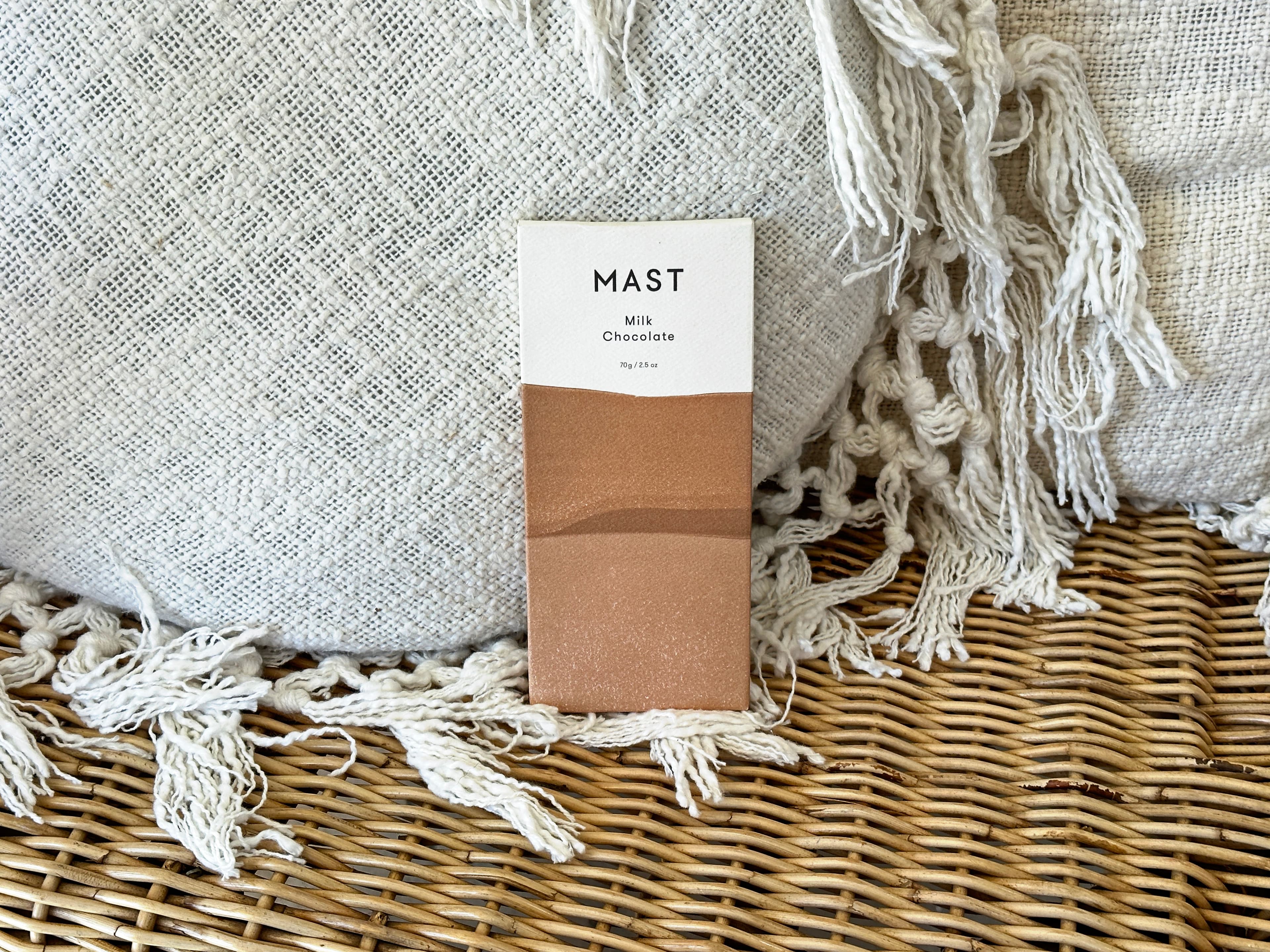 Milk Chocolate bar made by Mast in the United States with on a wicker chair with textured white pillows