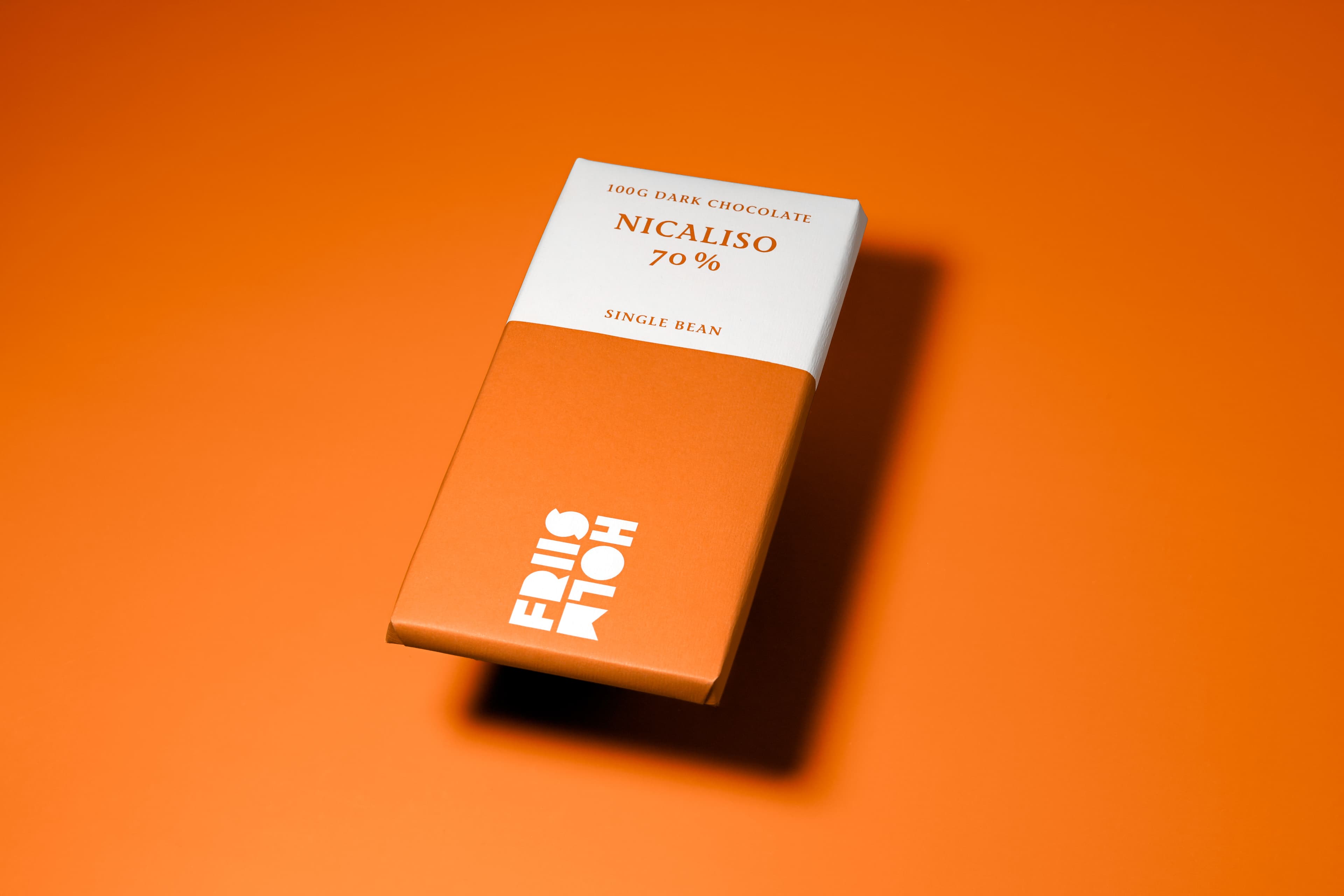 Nicaliso 70% bar made by Friis-Holm Chokolade in Denmark with slightly floating on an ornage background that matches the bar