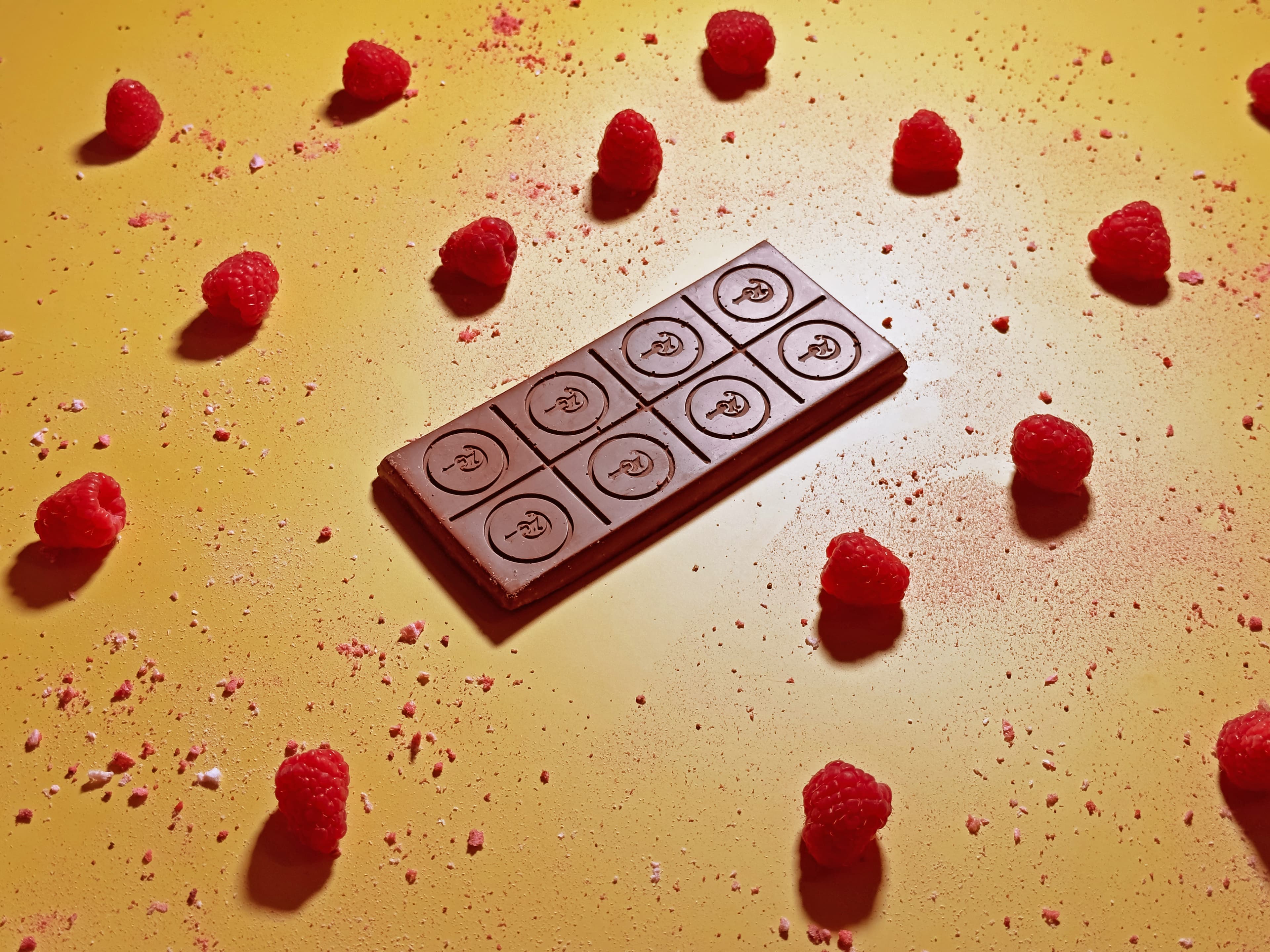 Pacific Razz Crisp bar made by Pacific Chocolate Company in the United States on a yellow background with raspberries