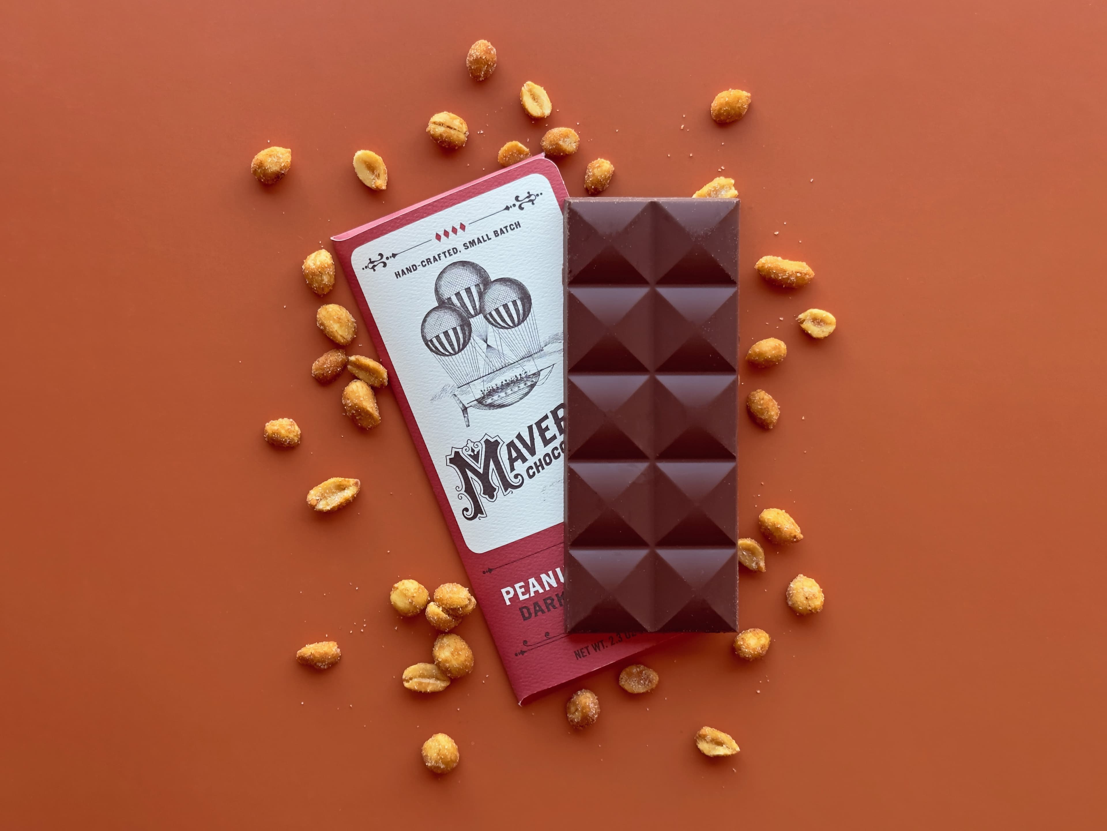 Peanut Butter Dark Chocolate bar made by Maverick Chocolate Co in the United States on an orange background with peanuts