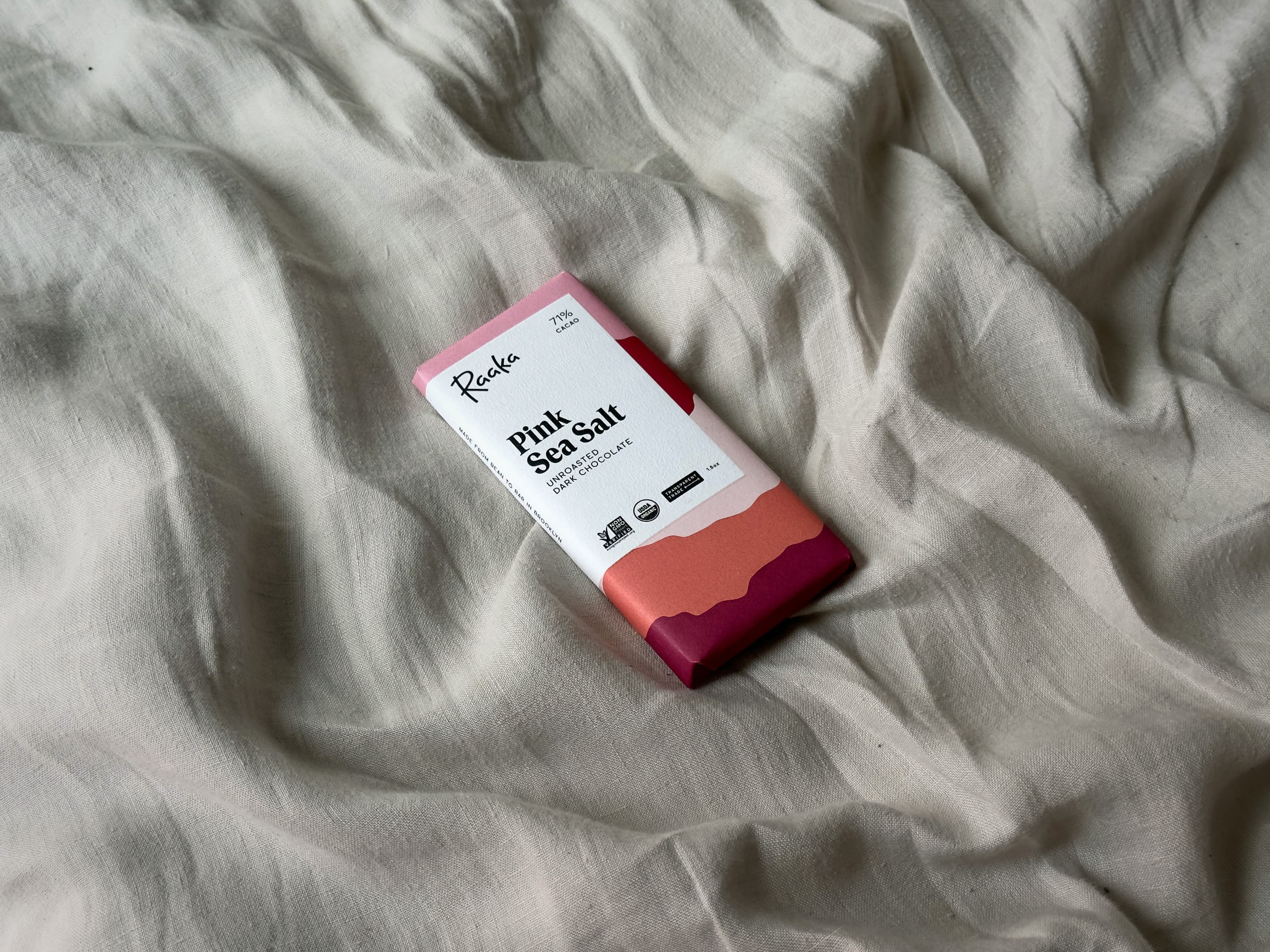 Pink Sea Salt Unroasted Dark Chocolate bar from Raaka Chocolate on rippled linen tablecloth