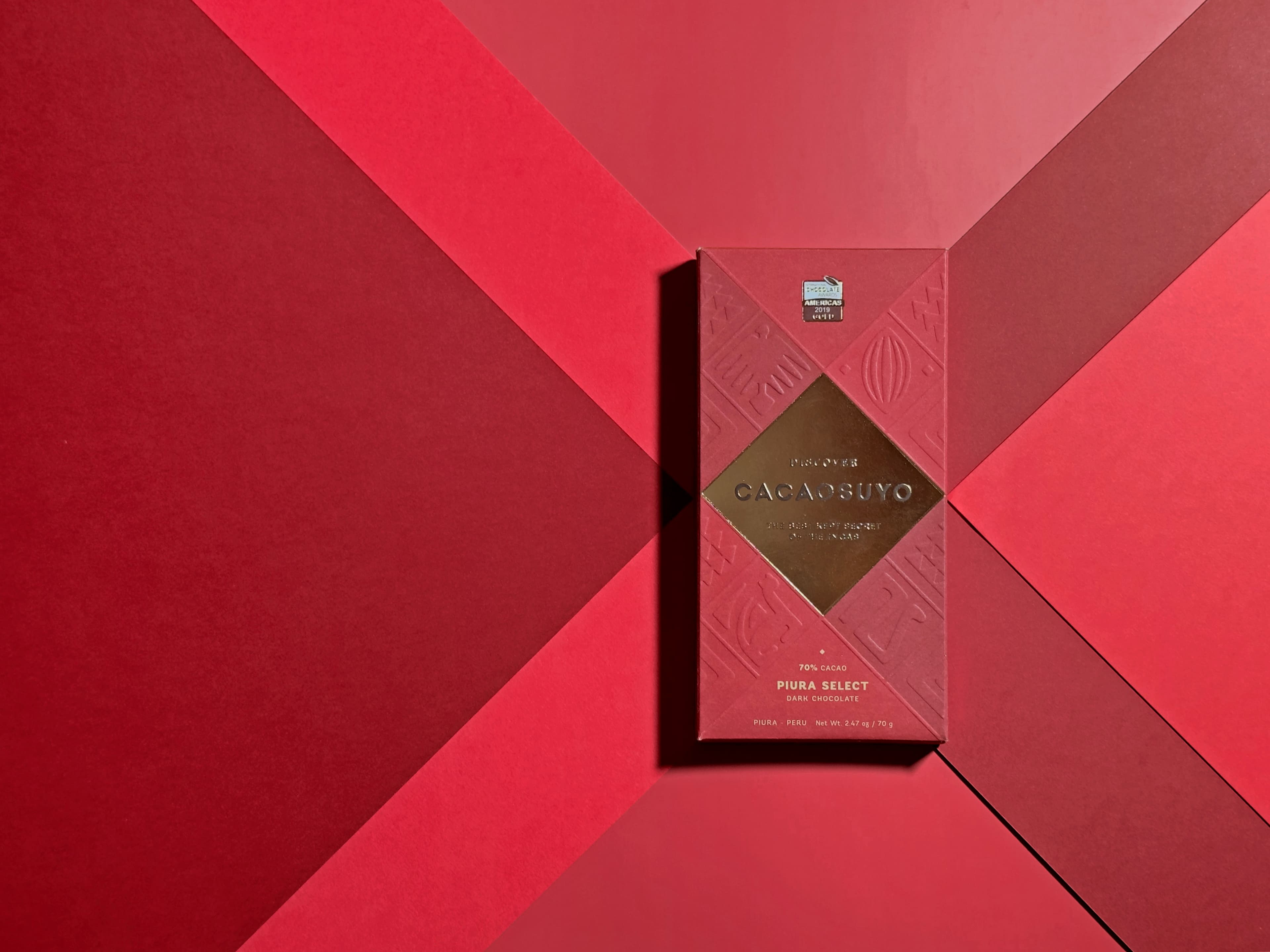 Piura Select Dark Chocolate bar made by Cacaosuyo in Peru on a geometric red background