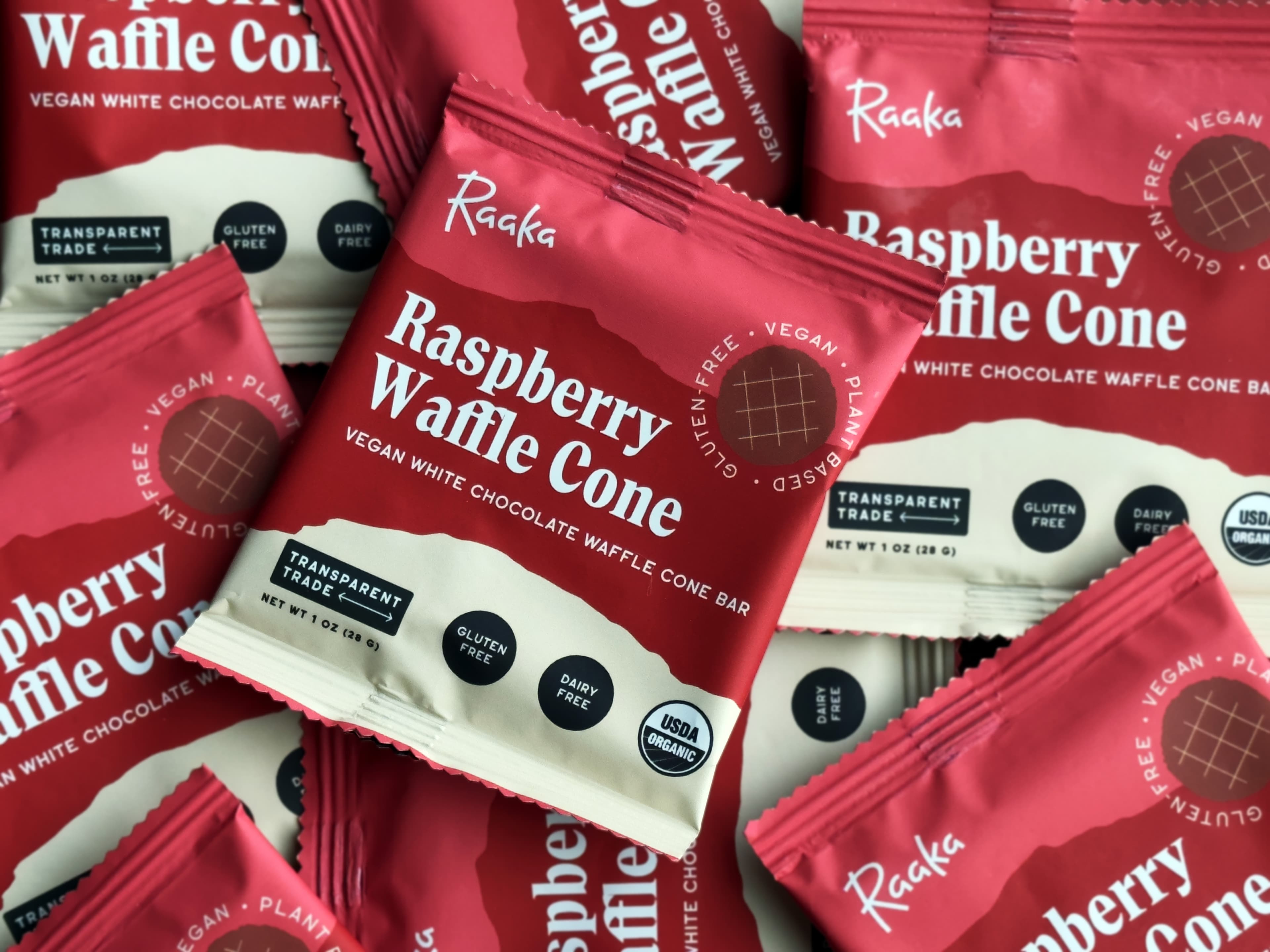 Raspberry Waffle Cone Vegan White Chocolate Waffle Cone bar made by Raaka Chocolate in the United States in a big pile of bars