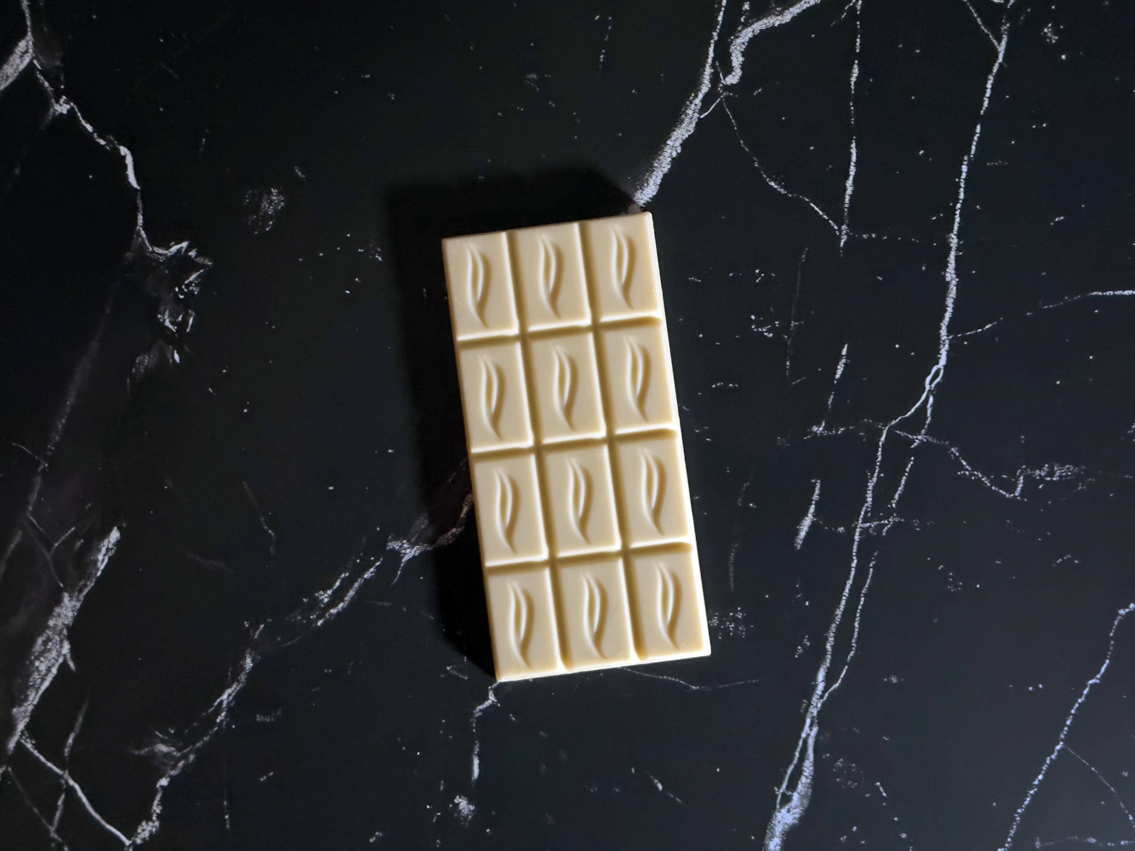 Vegan White Bar With Organic Vanilla bar made by Pascha Chocolate Co in Peru on a geometric red background