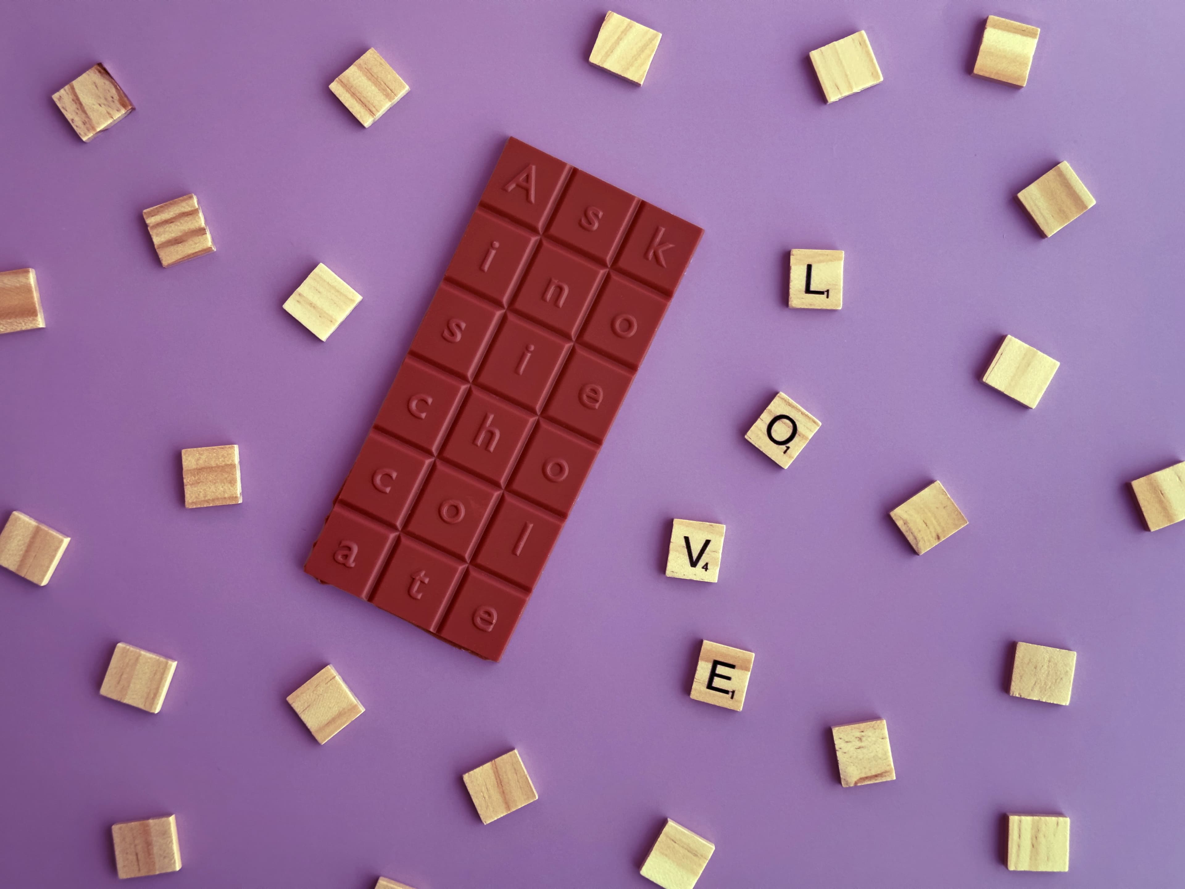 (White) Chocolate Covered Strawberry bar made by Askinosie Chocolate in the United States with scrabble tiles spelling out "Love"